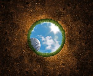 Golf ball falling over the edge into the hole